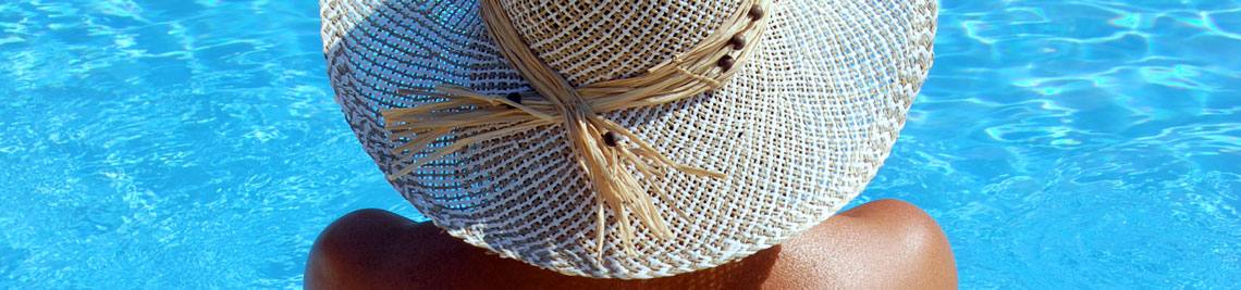 Naturist by pool wearing only a sun hat in the Greek Island of Kefalonia